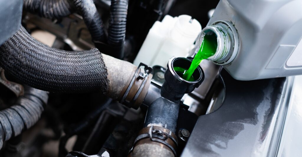 Mechanic performing car coolant replacement to prevent engine overheating and corrosion